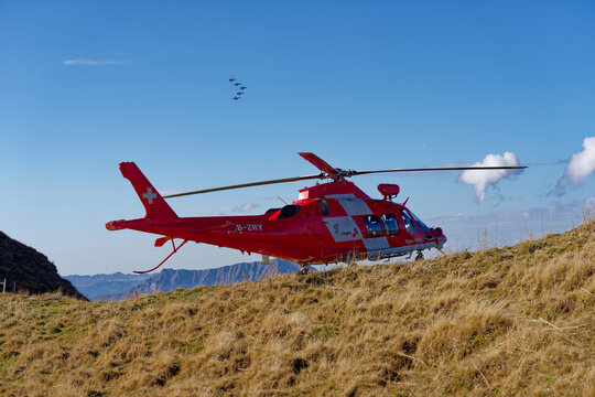 Parked red and white Rega rescue helicopter Agusta A109 register HB-ZRY at Air Display Axalp 2022 on a sunny autumn day. Photo taken October 18th, 2022, Axalp, Switzerland.