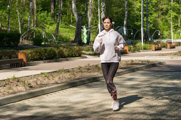 Young fitness woman running at morning city park, full shot