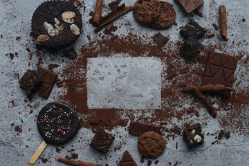 Blank square space for text space surrounded by various chocolate stuff isolated on gray background. 
