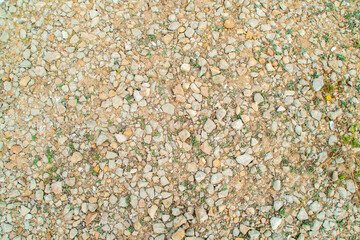 Background with gravel and grass growing between the stones. Small pieces of granite scattered on the ground.