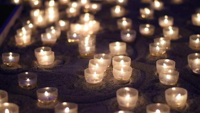 Small candles, religious scene in cathedral, hand enlightening candle.