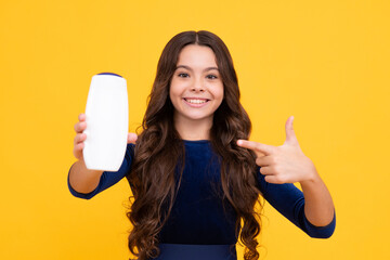 Child with shampoo conditioner. Daily cosmetic care. Teenager hold bottle of hair and skin care. Beauty health and cosmetics. Happy face, positive and smiling emotions of teenager girl.