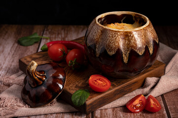 Red tomatoes and baked potatoes in a pot lie on the table in the kitchen
