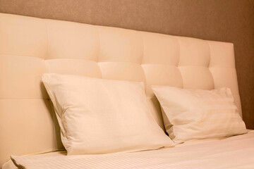 a bed with a high leather headboard and pillows