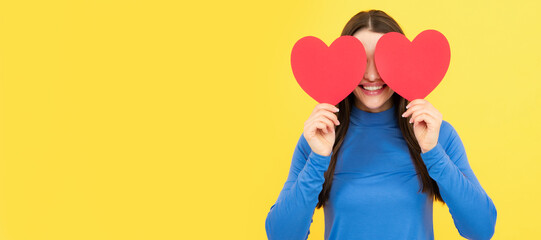 Happy woman hold red heart. Beautiful female model posing on isolated yellow background. Woman isolated face portrait, banner with copy space.