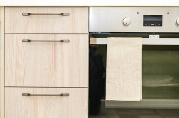 Kitchen cabinet, hob and oven. fragment of modern kitchen interior close-up. Wooden facade of the...