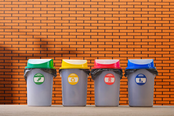 Multi Colored garbage bins on pavement with blurred artificial brick wall background