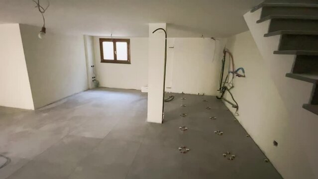 Laying the ceramic tiles on the basement room floor. Clean empty room after treatment
