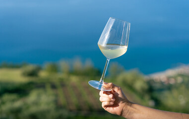 glass of wine in hand Relaxed Woman Enjoying White Wine with Ocean View at a Vineyard