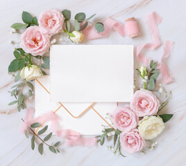 Blank card between pink roses and pink silk ribbons top view, wedding mockup
