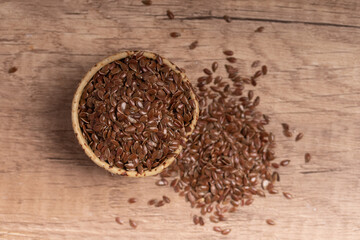 flax seeds in a wooden bowl on a wooden background, top view