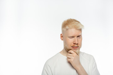 pensive albino man touching beard while thinking on white background