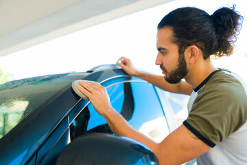 Latin young man polishing his car