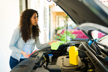 Young woman changing the oil of her car