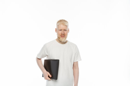 happy albino freelancer man in t-shirt holding laptop isolated on white