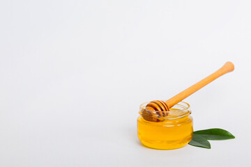 Honey in jar with leaves and honey dipper on colored background top view with copy text