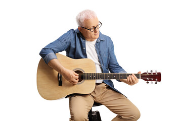 Mature musician sitting on a chair and playing an acoustic guitar