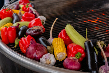 Process of grilling healthy vegetables - pepper, corn, zucchini, onion, garlic on brazier at summer outdoor food market - close up. Professional cooking, cookery, vegetarian and street food concept