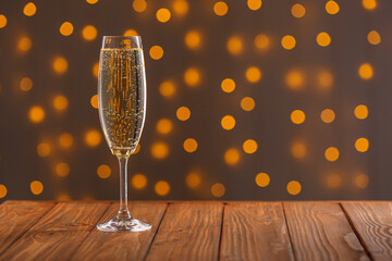 Glasses with champagne on a wooden background against a bokeh background of lights © Minakryn Ruslan 