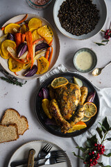 Dinner with oven baked spring chicken (coquelet jaune) in French herbs and citruses, baked vegetables and lentils on white background.