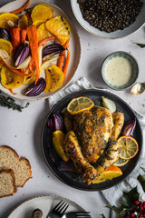 Dinner with oven baked spring chicken (coquelet jaune) in French herbs and citruses, baked vegetables and lentils on white background.