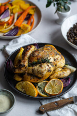 Dinner with oven baked spring chicken (coquelet jaune) in French herbs and citruses, baked vegetables and lentils on white background.