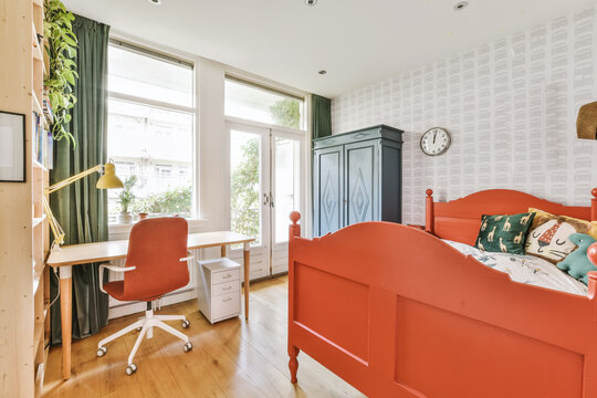 A Child's Room With An Orange Bed, Desk And Chair In The Fore - Image Is Taken From Above