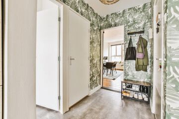a hallway with green and white wallpaper on the walls, an entry way leading to another room is in...