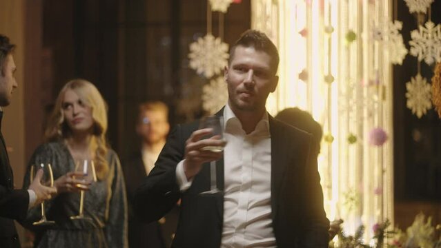attractive man in black suit dancing alone on dance floor in merry New year party with friends