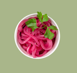 Pickled red onion rings in a white bowl with fresh herbs on green background. Healthy fermented...