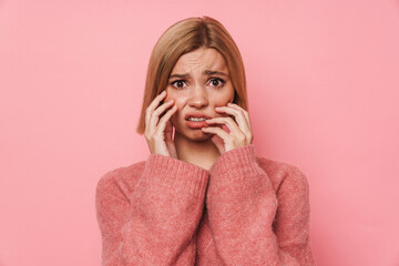 Disgusted young girl touching her face and looking at camera isolated over pink background