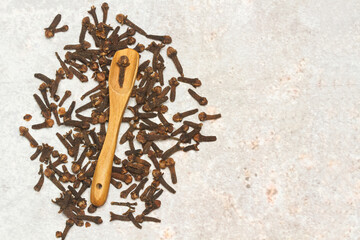 Clavo de olor junto a una cuchara de madera sobre un fondo rústico. Vista superior y de cerca. Copy space. Macro