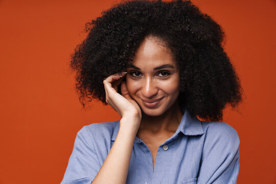 Smiling African American Woman Standing With Hand On Chin Isolated Over Red Wall