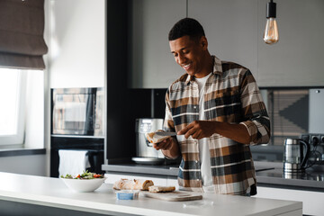 Young african man cooking in kitchen at home