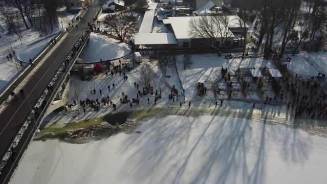 the drone flies over the hole in the winter rake, the river is covered with ice, people enter the cold water, cross themselves and plunge headlong into the ice water three times
