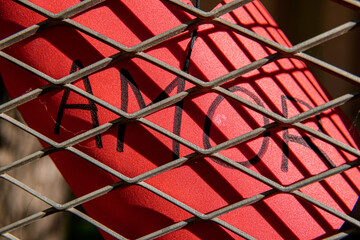 A red paper heart with the word love inside a cage. Forbidden love. Valentine's Day.