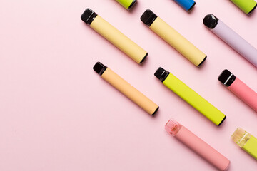 Disposable electronic cigarettes on color background, top view