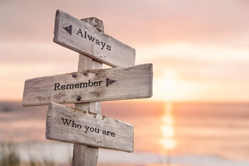 always remember who you are text quote engraved on wooden signpost outdoors at the beach. Sunset...