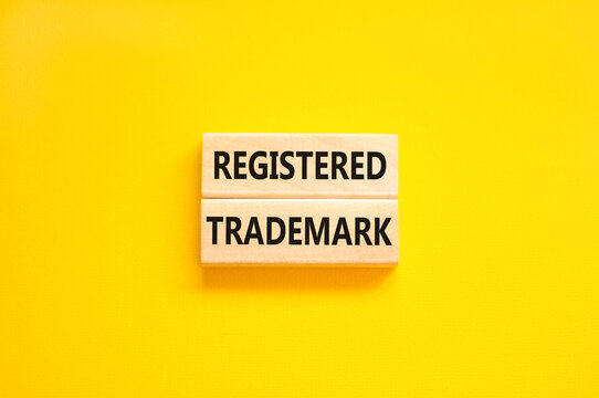 Registered trademark symbol. Concept word Registered trademark on wooden blocks. Beautiful yellow table yellow background. Business and registered trademark concept. Copy space.