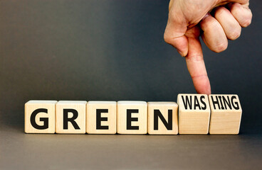 Green or greenwashing symbol. Concept words Green and Greenwashing on wooden cubes. Businessman hand. Beautiful grey table grey background. Business green greenwashing concept. Copy space.