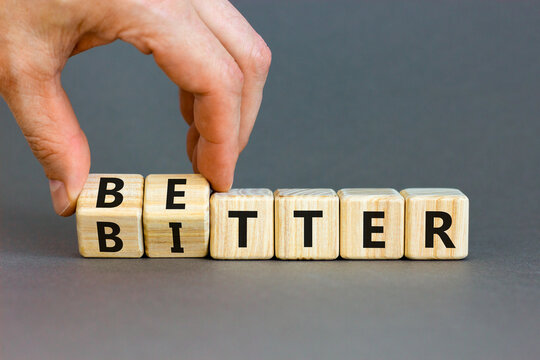 Better or bitter symbol. Concept word Better and Bitter on wooden cubes. Businessman hand. Beautiful grey table grey background. Business and better or bitter concept. Copy space.