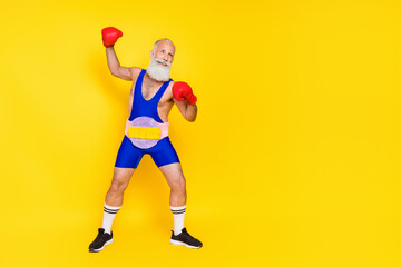 Fototapeta na wymiar Full size photo of handsome sportive person wear boxing gloves soft fluffy belt look empty space isolated on yellow color background