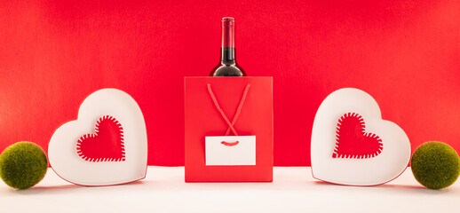 Fond d'écran avec des cœurs rouges pour la Saint-Valentin avec un paquet cadeau et du vin rouge....