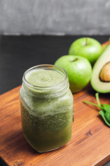 Green smoothie drink blended in a glass jar, avocado, spinach leaves and apples at wooden board