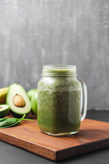 Green smoothie drink blended in a glass jar, avocado, spinach leaves and apples at wooden board