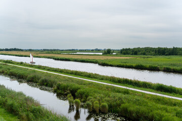 View over nature reserve and sail boat from Romsich (wideview) viewing platform in Earnewald in Fryslan (Friesland, The Netherlands) a national park with water, marshes and peatland.