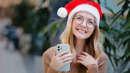 Happy amazed success Caucasian woman girl lady in red Santa Claus Christmas hat and eyeglass win...