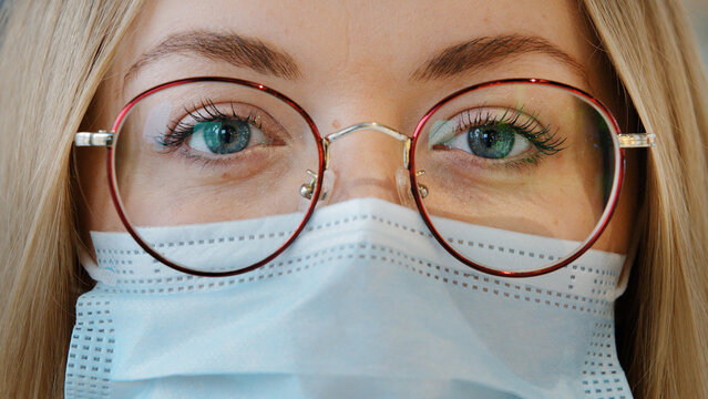 Extreme Close Up Female Face Caucasian Girl Woman With Blue Eyes Wear Glasses And Medical Mask Female Doctor Nurse Lab Worker In Respirator And Eyewear Looking At Camera Protection From Covid Pandemic