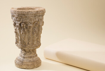 catholic, stone chalice with bible next to it on a light beige background