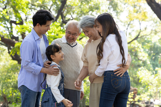 Happy Multi-generation Asian family smiling and hugging in the park, Big family standing in the public garden concept